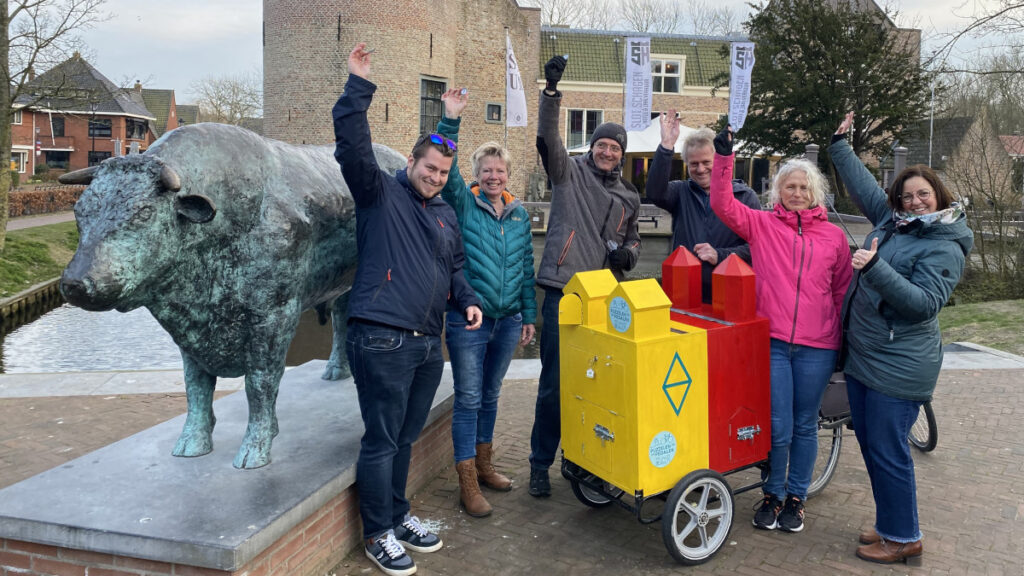 Een groep mensen staan met hun arm in de lucht. Wie is er klaar om te starten met Puzzelen op de Pedalen?