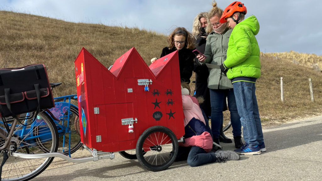 Vijf personen proberen een puzzel in de fietskar op te lossen tijdens Puzzelen op de Pedalen.