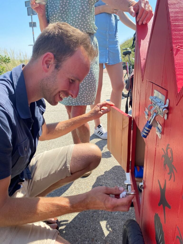 Een man heeft een vakje van de puzzelkar geopend en bekijkt wat er in zit.